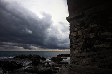 Deniz kıyısındaki bir viyadük kemerleri, bir dalgakıranın kayaları üzerinde, alacakaranlıkta bulutlu bir günde görülür.