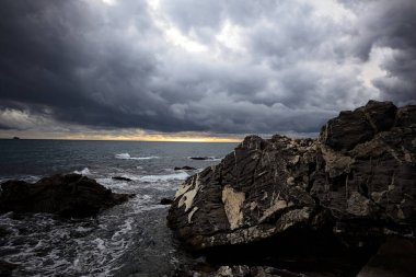 Breakwater with water crushing on its rocks on a cloudy day at twilight