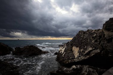 Breakwater with water crushing on its rocks on a cloudy day at twilight