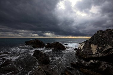 Breakwater with water crushing on its rocks on a cloudy day at twilight