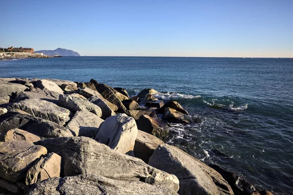 Küçük bir körfezden görünen ve dalgakıran kayaları tarafından çerçevelenen binalar ve uçurumun kenarındaki bir çıkıntının ucu.