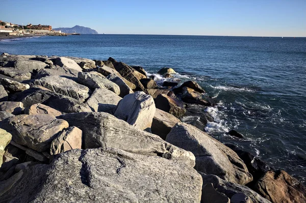 Küçük bir körfezden görünen ve dalgakıran kayaları tarafından çerçevelenen binalar ve uçurumun kenarındaki bir çıkıntının ucu.
