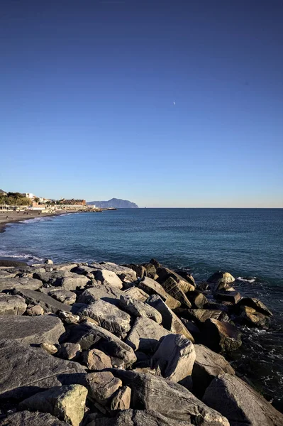 Küçük bir körfezden görünen ve dalgakıran kayaları tarafından çerçevelenen binalar ve uçurumun kenarındaki bir çıkıntının ucu.