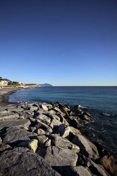 Küçük bir körfezden görünen ve dalgakıran kayaları tarafından çerçevelenen binalar ve uçurumun kenarındaki bir çıkıntının ucu.