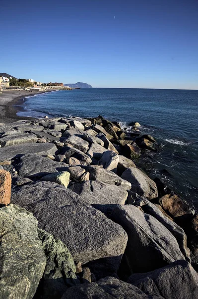 Küçük bir körfezden görünen ve dalgakıran kayaları tarafından çerçevelenen binalar ve uçurumun kenarındaki bir çıkıntının ucu.