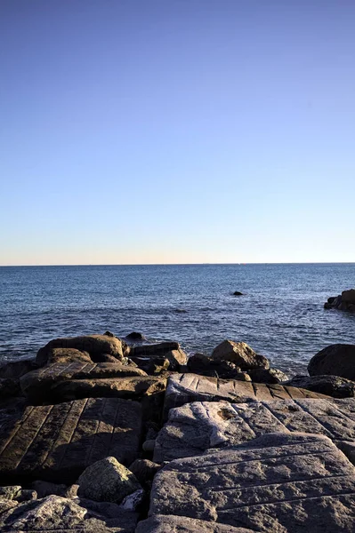 Gün batımında bir uçurumun kayaları su seviyesinde görülür ve deniz Horizon 'a kadar uzanır.