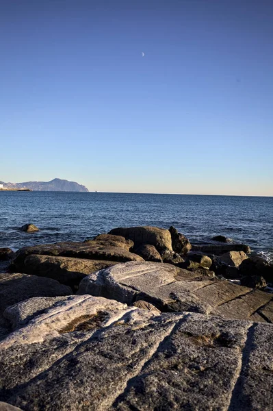 Küçük bir körfezden görünen ve dalgakıran kayaları tarafından çerçevelenen binalar ve uçurumun kenarındaki bir çıkıntının ucu.