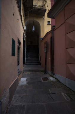 Dar ve dik tırmanma merdivenleri kapalı bir geçitin altından geçiyor. Bir İtalyan kasabasının arka sokağında.