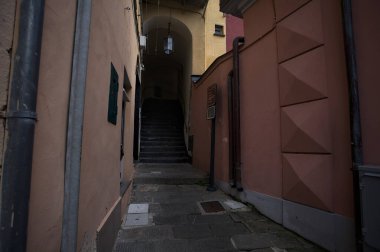 Dar ve dik tırmanma merdivenleri kapalı bir geçitin altından geçiyor. Bir İtalyan kasabasının arka sokağında.