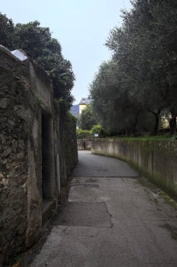İtalyan kasabasında bahçe ile taş duvar arasındaki dar yol.