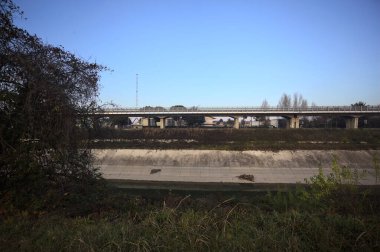 Günbatımında ağaçların çerçevelediği İtalya kırsalında, eğlence kanalının diğer ucundaki viyadük.