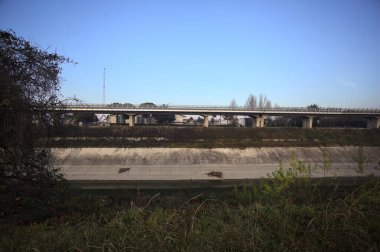 Günbatımında ağaçların çerçevelediği İtalya kırsalında, eğlence kanalının diğer ucundaki viyadük.