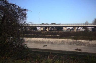 Günbatımında ağaçların çerçevelediği İtalya kırsalında, eğlence kanalının diğer ucundaki viyadük.