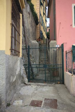 Bulutlu bir günde yeşil bir kapı tarafından engellenen tarihi binalar arasındaki dar merdivenler