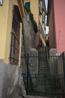 Bulutlu bir günde yeşil bir kapı tarafından engellenen tarihi binalar arasındaki dar merdivenler