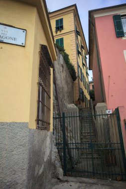 Bulutlu bir günde yeşil bir kapı tarafından engellenen tarihi binalar arasındaki dar merdivenler