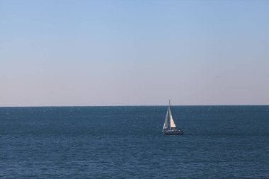 Sakin bir denizde yelken açmak güneşli bir günde ufka kadar uzanan açık bir gökyüzü.