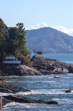 Evin etrafı kayalıklarla çevrili, kayalıklarla denize doğru uzanan kayalıklar ve güneşli bir günde uzak bir dağ sırtı ile çevrili.