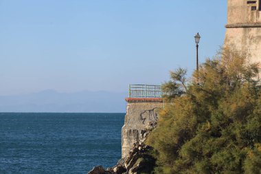 Güneşli bir günde, bir uçurumun kenarındaki ağaçların yanında balkon.