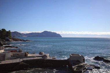 Evin etrafı kayalıklarla çevrili, kayalıklarla denize doğru uzanan kayalıklar ve güneşli bir günde uzak bir dağ sırtı ile çevrili.