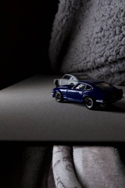 Mantova, İtalya - 3RD JANUARY 2025 Takara Tomy kopyaları gri Nissan Skyline 2000 GT-R ve mavi Nissan Fairlady Z beyaz bir panoda, gri bir kumaş parçasının yanında, uçurumun kenarındaki bir dağ yolunda yarış yapıyormuş gibi yapıyor.