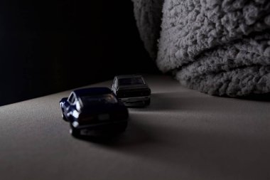 Mantova, İtalya - 3RD JANUARY 2025 Takara Tomy kopyaları gri Nissan Skyline 2000 GT-R ve mavi Nissan Fairlady Z beyaz bir panoda, gri bir kumaş parçasının yanında, uçurumun kenarındaki bir dağ yolunda yarış yapıyormuş gibi yapıyor.