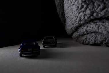 Mantova, İtalya - 3RD JANUARY 2025 Takara Tomy kopyaları gri Nissan Skyline 2000 GT-R ve mavi Nissan Fairlady Z beyaz bir panoda, gri bir kumaş parçasının yanında, uçurumun kenarındaki bir dağ yolunda yarış yapıyormuş gibi yapıyor.