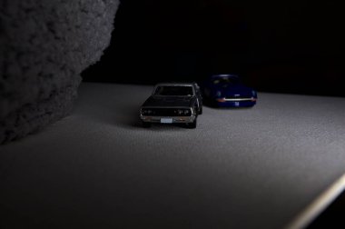 Mantova, İtalya - 3RD JANUARY 2025 Takara Tomy kopyaları gri Nissan Skyline 2000 GT-R ve mavi Nissan Fairlady Z beyaz bir panoda, gri bir kumaş parçasının yanında, uçurumun kenarındaki bir dağ yolunda yarış yapıyormuş gibi yapıyor.