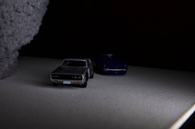 Mantova, İtalya - 3RD JANUARY 2025 Takara Tomy kopyaları gri Nissan Skyline 2000 GT-R ve mavi Nissan Fairlady Z beyaz bir panoda, gri bir kumaş parçasının yanında, uçurumun kenarındaki bir dağ yolunda yarış yapıyormuş gibi yapıyor.