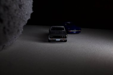 Mantova, İtalya - 3RD JANUARY 2025 Takara Tomy kopyaları gri Nissan Skyline 2000 GT-R ve mavi Nissan Fairlady Z beyaz bir panoda, gri bir kumaş parçasının yanında, uçurumun kenarındaki bir dağ yolunda yarış yapıyormuş gibi yapıyor.