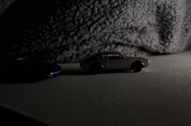 Mantova, İtalya - 3RD JANUARY 2025 Takara Tomy kopyaları gri Nissan Skyline 2000 GT-R ve mavi Nissan Fairlady Z beyaz bir panoda, gri bir kumaş parçasının yanında, uçurumun kenarındaki bir dağ yolunda yarış yapıyormuş gibi yapıyor.