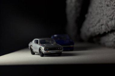 Mantova, İtalya - 3RD JANUARY 2025 Takara Tomy kopyaları gri Nissan Skyline 2000 GT-R ve mavi Nissan Fairlady Z beyaz bir panoda, gri bir kumaş parçasının yanında, uçurumun kenarındaki bir dağ yolunda yarış yapıyormuş gibi yapıyor.