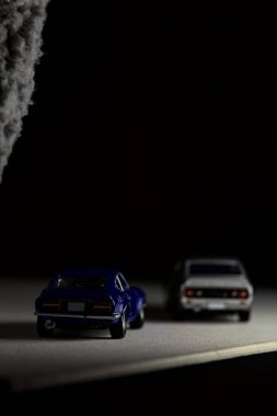 Mantova, İtalya - 3RD JANUARY 2025 Takara Tomy kopyaları gri Nissan Skyline 2000 GT-R ve mavi Nissan Fairlady Z beyaz bir panoda, gri bir kumaş parçasının yanında, uçurumun kenarındaki bir dağ yolunda yarış yapıyormuş gibi yapıyor.