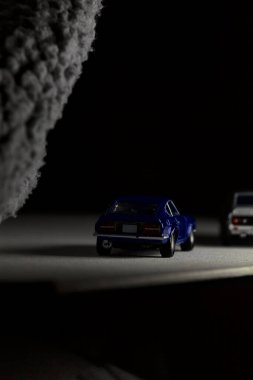 Mantova, İtalya - 3RD JANUARY 2025 Takara Tomy kopyaları gri Nissan Skyline 2000 GT-R ve mavi Nissan Fairlady Z beyaz bir panoda, gri bir kumaş parçasının yanında, uçurumun kenarındaki bir dağ yolunda yarış yapıyormuş gibi yapıyor.