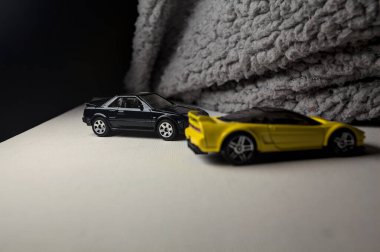 Mantova, İtalya - 3RD JANUARY 2025 - 1990 model Acura NSX ve 1984 model Toyota MR2 'nin kopyaları, gri bir kumaş parçasının yanında, uçurumun kenarındaki bir dağ yolunda yarış yapıyormuş gibi yapıyor.