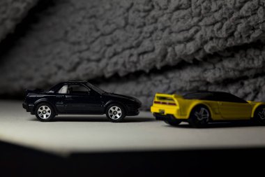Mantova, İtalya - 3RD JANUARY 2025 - 1990 model Acura NSX ve 1984 model Toyota MR2 'nin kopyaları, gri bir kumaş parçasının yanında, uçurumun kenarındaki bir dağ yolunda yarış yapıyormuş gibi yapıyor.