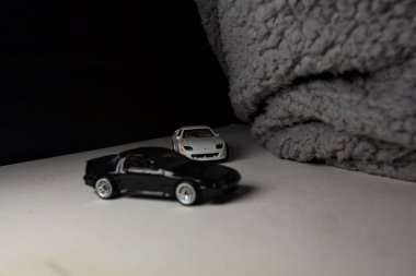 Mantova, İtalya - 3RD JANUARY 2025 - 1989 Mazda Savanna RX-7 'nin Ateşli Tekerlekleri ve Kibrit kutusu kopyaları ve beyaz bir tahtanın üzerinde beyaz bir kumaş parçasının yanında, uçurumun kenarındaki bir dağ yolunda yarış yapıyormuş gibi yapan Mitsubishi 3000 GT