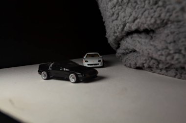 Mantova, İtalya - 3RD JANUARY 2025 - 1989 Mazda Savanna RX-7 'nin Ateşli Tekerlekleri ve Kibrit kutusu kopyaları ve beyaz bir tahtanın üzerinde beyaz bir kumaş parçasının yanında, uçurumun kenarındaki bir dağ yolunda yarış yapıyormuş gibi yapan Mitsubishi 3000 GT