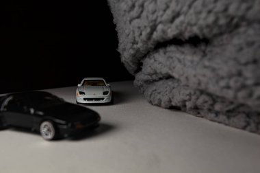 Mantova, İtalya - 3RD JANUARY 2025 - 1989 Mazda Savanna RX-7 'nin Ateşli Tekerlekleri ve Kibrit kutusu kopyaları ve beyaz bir tahtanın üzerinde beyaz bir kumaş parçasının yanında, uçurumun kenarındaki bir dağ yolunda yarış yapıyormuş gibi yapan Mitsubishi 3000 GT