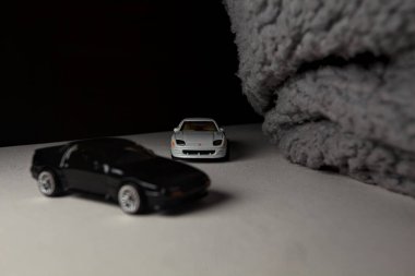 Mantova, İtalya - 3RD JANUARY 2025 - 1989 Mazda Savanna RX-7 'nin Ateşli Tekerlekleri ve Kibrit kutusu kopyaları ve beyaz bir tahtanın üzerinde beyaz bir kumaş parçasının yanında, uçurumun kenarındaki bir dağ yolunda yarış yapıyormuş gibi yapan Mitsubishi 3000 GT