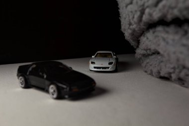 Mantova, İtalya - 3RD JANUARY 2025 - 1989 Mazda Savanna RX-7 'nin Ateşli Tekerlekleri ve Kibrit kutusu kopyaları ve beyaz bir tahtanın üzerinde beyaz bir kumaş parçasının yanında, uçurumun kenarındaki bir dağ yolunda yarış yapıyormuş gibi yapan Mitsubishi 3000 GT