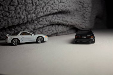 Mantova, İtalya - 3RD JANUARY 2025 - 1989 Mazda Savanna RX-7 'nin Ateşli Tekerlekleri ve Kibrit kutusu kopyaları ve beyaz bir tahtanın üzerinde beyaz bir kumaş parçasının yanında, uçurumun kenarındaki bir dağ yolunda yarış yapıyormuş gibi yapan Mitsubishi 3000 GT