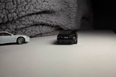 Mantova, İtalya - 3RD JANUARY 2025 - 1989 Mazda Savanna RX-7 'nin Ateşli Tekerlekleri ve Kibrit kutusu kopyaları ve beyaz bir tahtanın üzerinde beyaz bir kumaş parçasının yanında, uçurumun kenarındaki bir dağ yolunda yarış yapıyormuş gibi yapan Mitsubishi 3000 GT