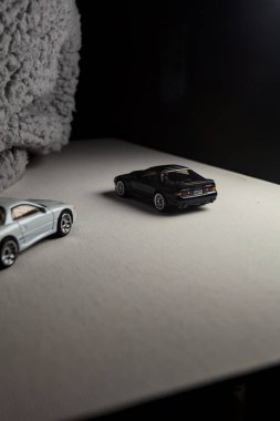 Mantova, İtalya - 3RD JANUARY 2025 - 1989 Mazda Savanna RX-7 'nin Ateşli Tekerlekleri ve Kibrit kutusu kopyaları ve beyaz bir tahtanın üzerinde beyaz bir kumaş parçasının yanında, uçurumun kenarındaki bir dağ yolunda yarış yapıyormuş gibi yapan Mitsubishi 3000 GT