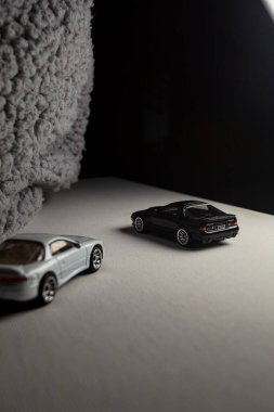 Mantova, İtalya - 3RD JANUARY 2025 - 1989 Mazda Savanna RX-7 'nin Ateşli Tekerlekleri ve Kibrit kutusu kopyaları ve beyaz bir tahtanın üzerinde beyaz bir kumaş parçasının yanında, uçurumun kenarındaki bir dağ yolunda yarış yapıyormuş gibi yapan Mitsubishi 3000 GT