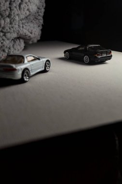 Mantova, İtalya - 3RD JANUARY 2025 - 1989 Mazda Savanna RX-7 'nin Ateşli Tekerlekleri ve Kibrit kutusu kopyaları ve beyaz bir tahtanın üzerinde beyaz bir kumaş parçasının yanında, uçurumun kenarındaki bir dağ yolunda yarış yapıyormuş gibi yapan Mitsubishi 3000 GT