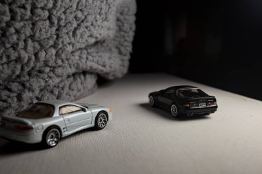 Mantova, İtalya - 3RD JANUARY 2025 - 1989 Mazda Savanna RX-7 'nin Ateşli Tekerlekleri ve Kibrit kutusu kopyaları ve beyaz bir tahtanın üzerinde beyaz bir kumaş parçasının yanında, uçurumun kenarındaki bir dağ yolunda yarış yapıyormuş gibi yapan Mitsubishi 3000 GT