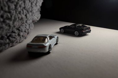 Mantova, İtalya - 3RD JANUARY 2025 - 1989 Mazda Savanna RX-7 'nin Ateşli Tekerlekleri ve Kibrit kutusu kopyaları ve beyaz bir tahtanın üzerinde beyaz bir kumaş parçasının yanında, uçurumun kenarındaki bir dağ yolunda yarış yapıyormuş gibi yapan Mitsubishi 3000 GT