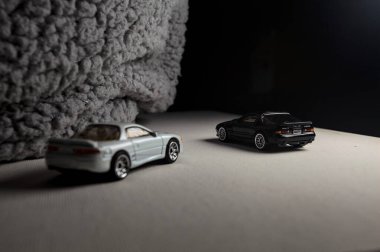 Mantova, İtalya - 3RD JANUARY 2025 - 1989 Mazda Savanna RX-7 'nin Ateşli Tekerlekleri ve Kibrit kutusu kopyaları ve beyaz bir tahtanın üzerinde beyaz bir kumaş parçasının yanında, uçurumun kenarındaki bir dağ yolunda yarış yapıyormuş gibi yapan Mitsubishi 3000 GT