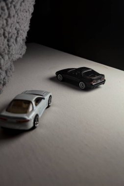 Mantova, İtalya - 3RD JANUARY 2025 - 1989 Mazda Savanna RX-7 'nin Ateşli Tekerlekleri ve Kibrit kutusu kopyaları ve beyaz bir tahtanın üzerinde beyaz bir kumaş parçasının yanında, uçurumun kenarındaki bir dağ yolunda yarış yapıyormuş gibi yapan Mitsubishi 3000 GT